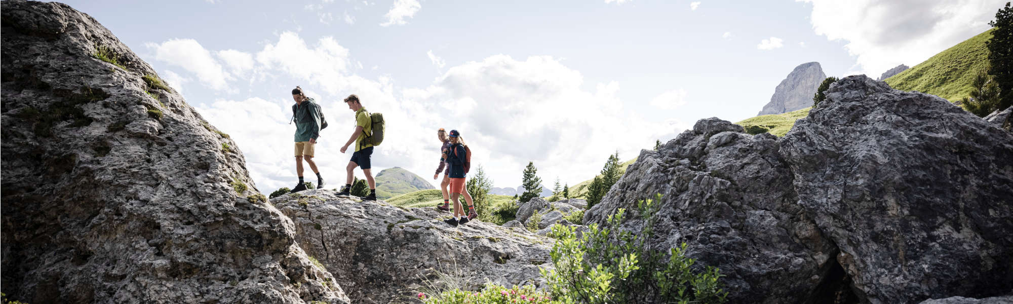VAUDE Fabrikverkauf Obereisenbach Vier junge Leute wandern in den Bergen über einen Felsen
