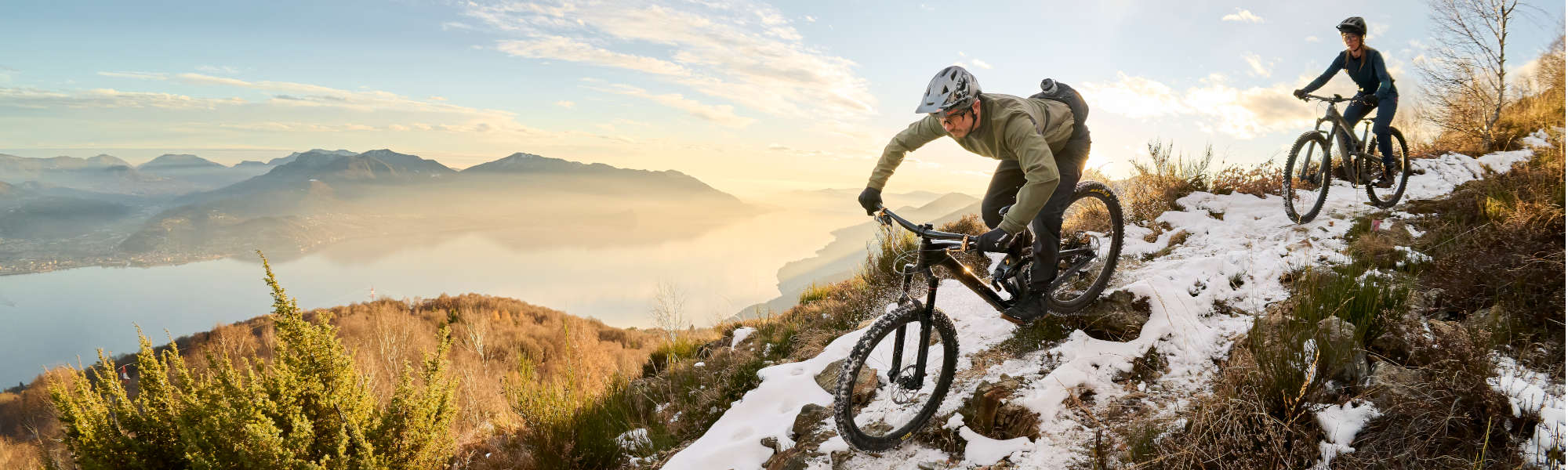 VAUDE Fabrikverkauf Obereisenbach Ein Mann und eine Frau fahren mit ihren Rädern auf einem schneebedeckten Berg