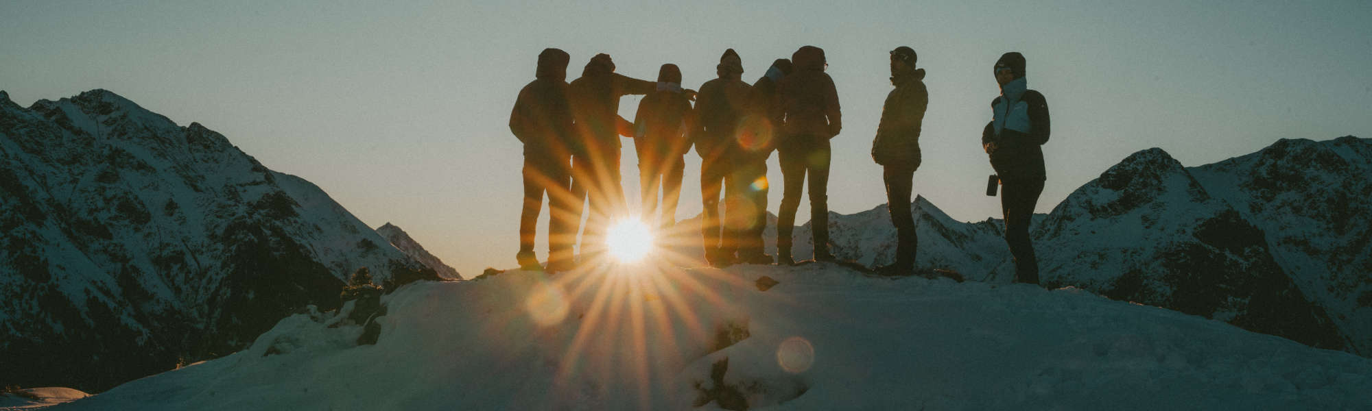 VAUDE Fabrikverkauf Obereisenbach Eine Gruppe Leute steht bei Sonnenuntergang auf einem Berg