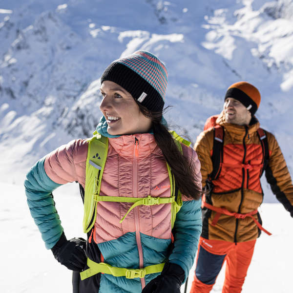 Eine Frau und Mann stehen in einer Schneelandschaft und blicken zur Seite