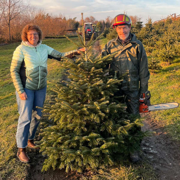 eine Frau und ein Mann stehen neben einer Tanne