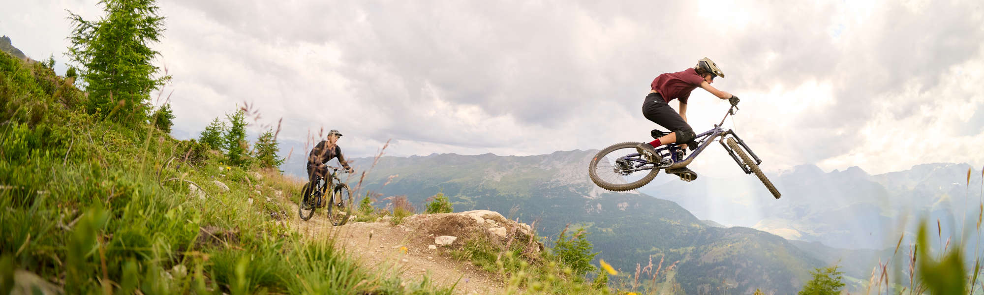 Zwei Leute fahren mit Mountainbikes einen Trail auf einem Berg