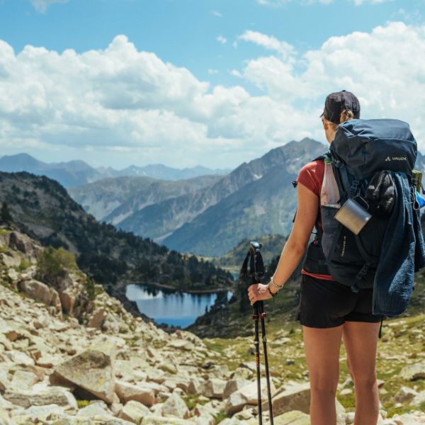 Hikerin mit großem Rucksack und Blick auf einen Bergsee